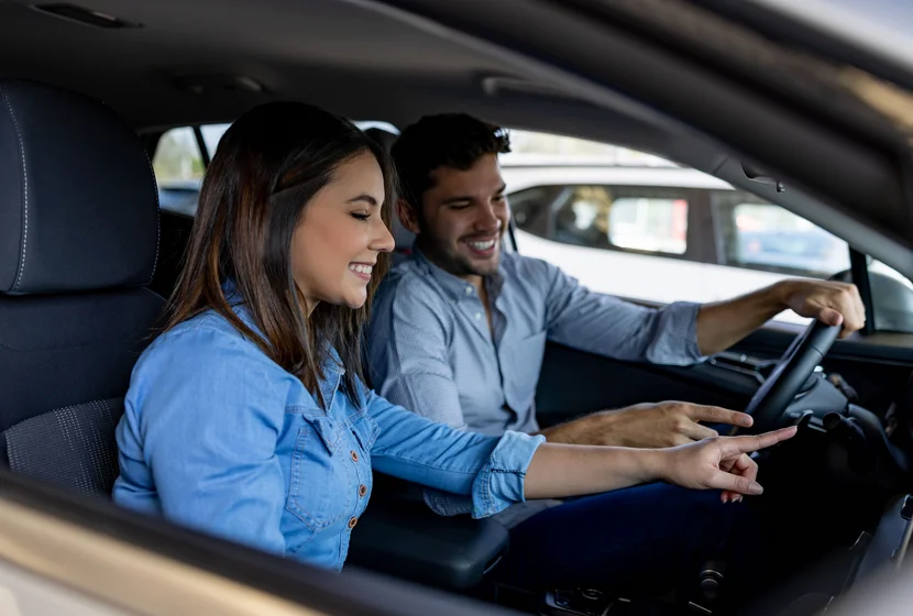 Happy Latin American couple looking at the interior of a car while shopping at the dealership